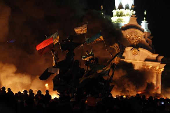 Anti-government protesters gather near a statue during clashes with riot police at Independence Square in Kiev